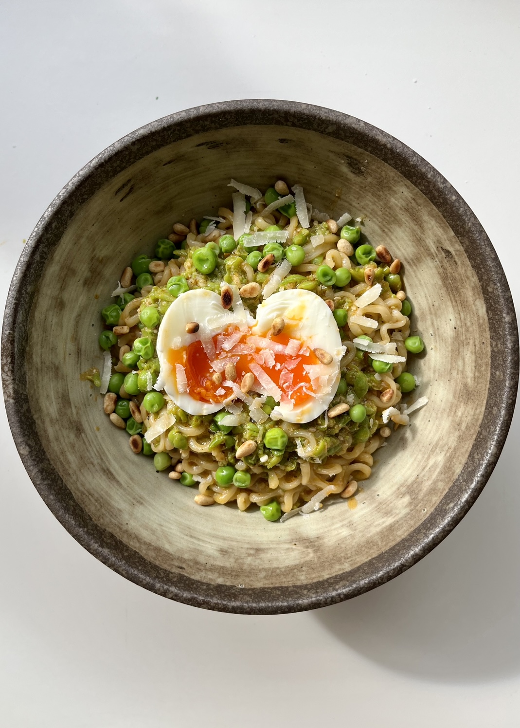 Pea Pesto Ramen in a brown bowl with a jammy egg.