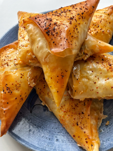 chili oil feta spinach pastries on a blue plate.