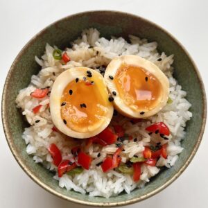 Miso marinated egg sliced open to show the yolk on a bed of rice.