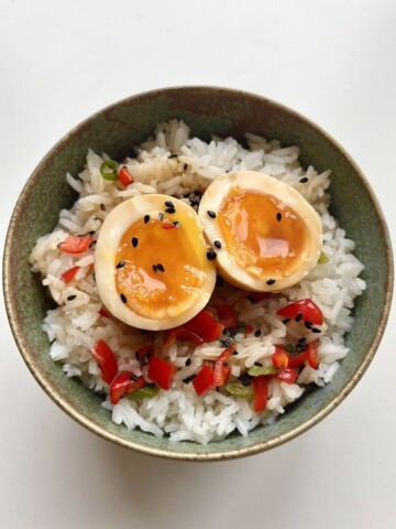 Miso marinated egg sliced open to show the yolk on a bed of rice.