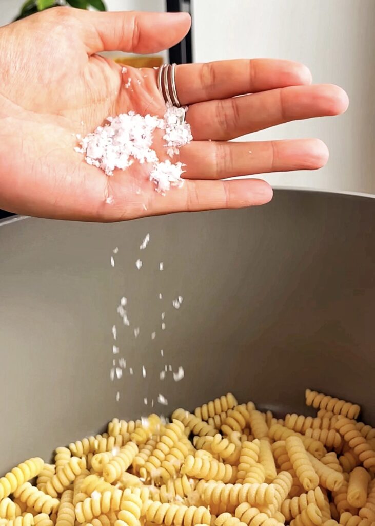 adding salt to a pan of pasta