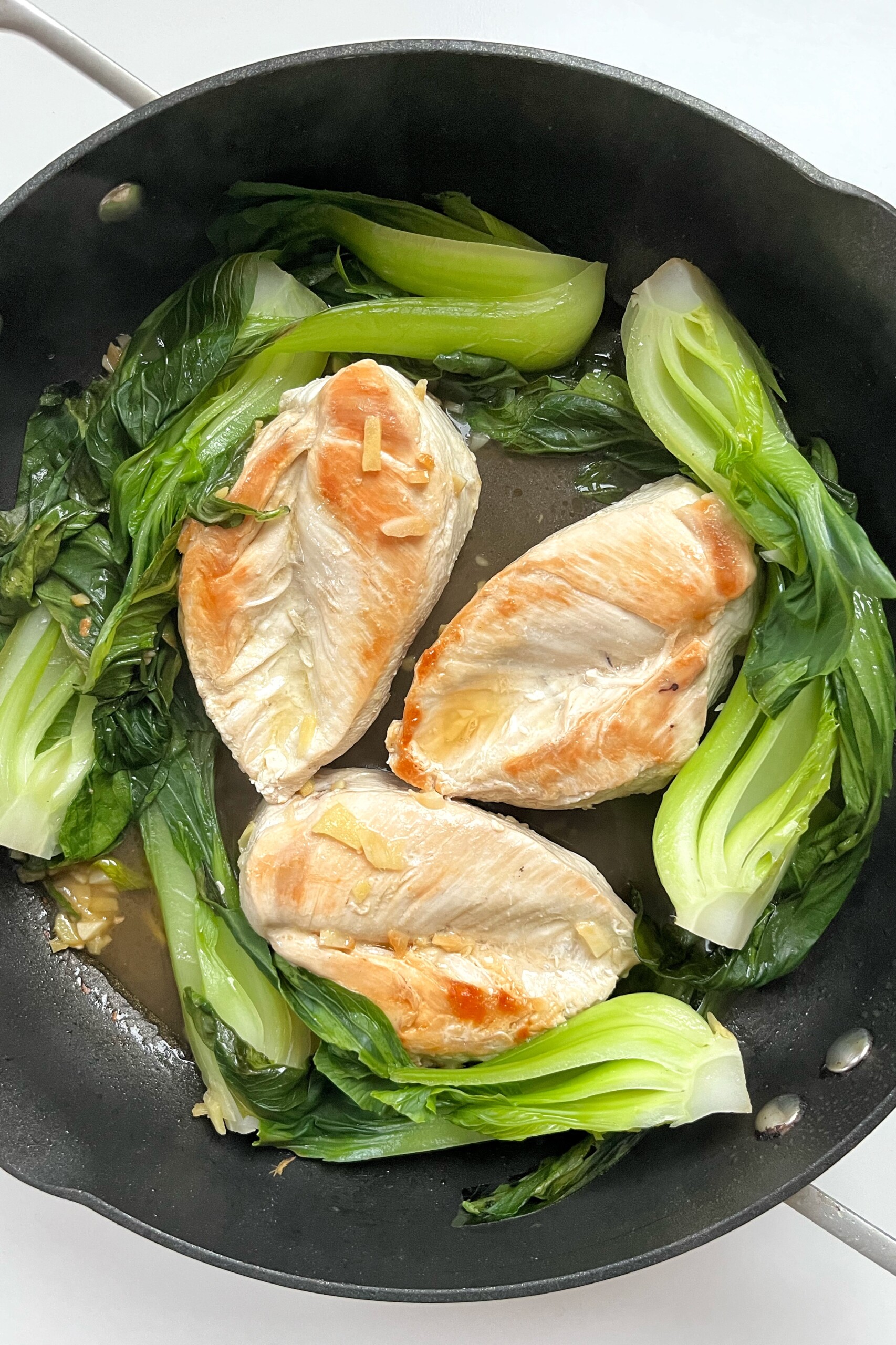 Chicken and pak choi in non-stick pan.
