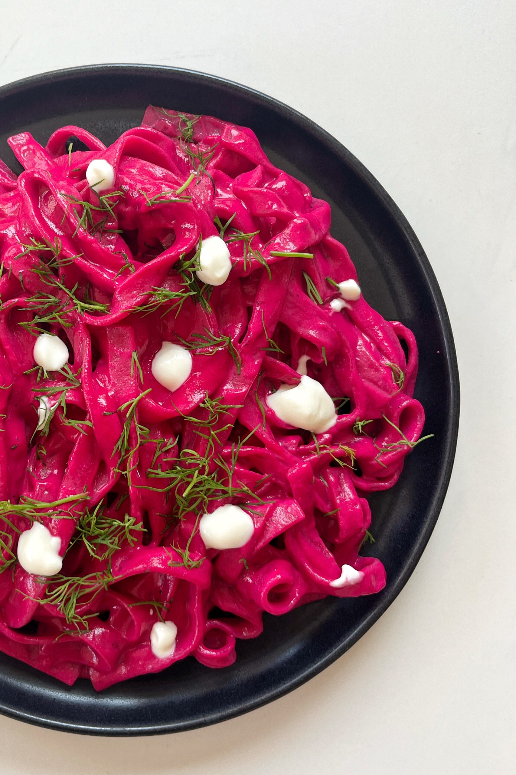 Pink pasta on a black plate.