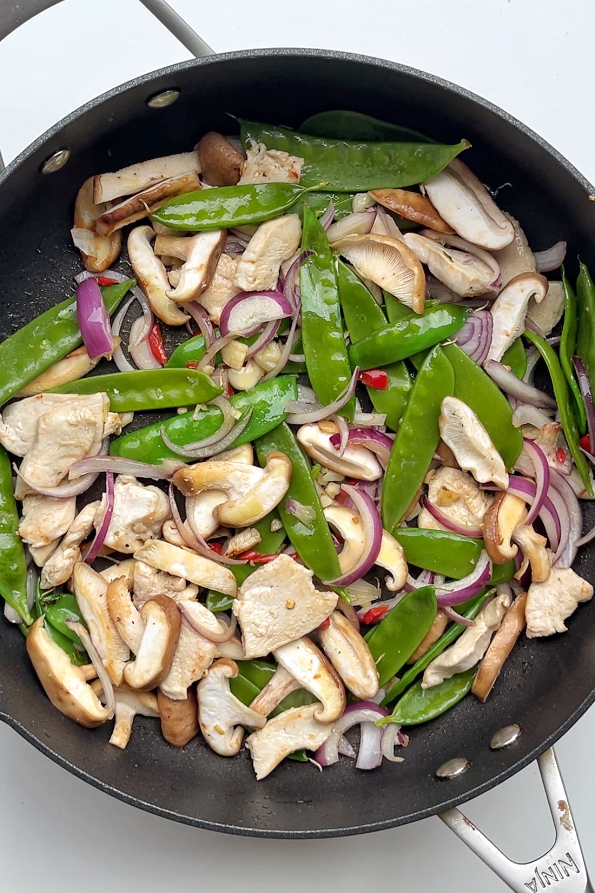 Stir fried vegetables in black frying pan.