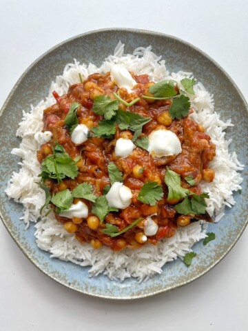 Aubergine tikka masala on blue plate.
