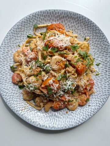 Creamy prawn and chorizo linguine on a light blue plate.