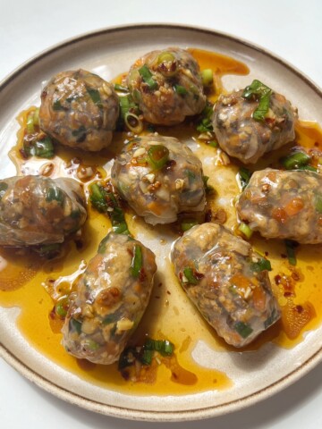 Steamed rice paper dumplings on a cream plate.