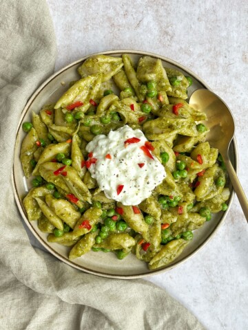 White background with a plate of green pasta.