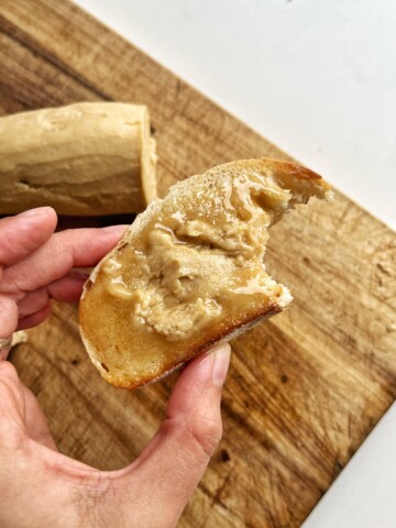 Close up of a person holding a piece of toast with espresso butter on it.