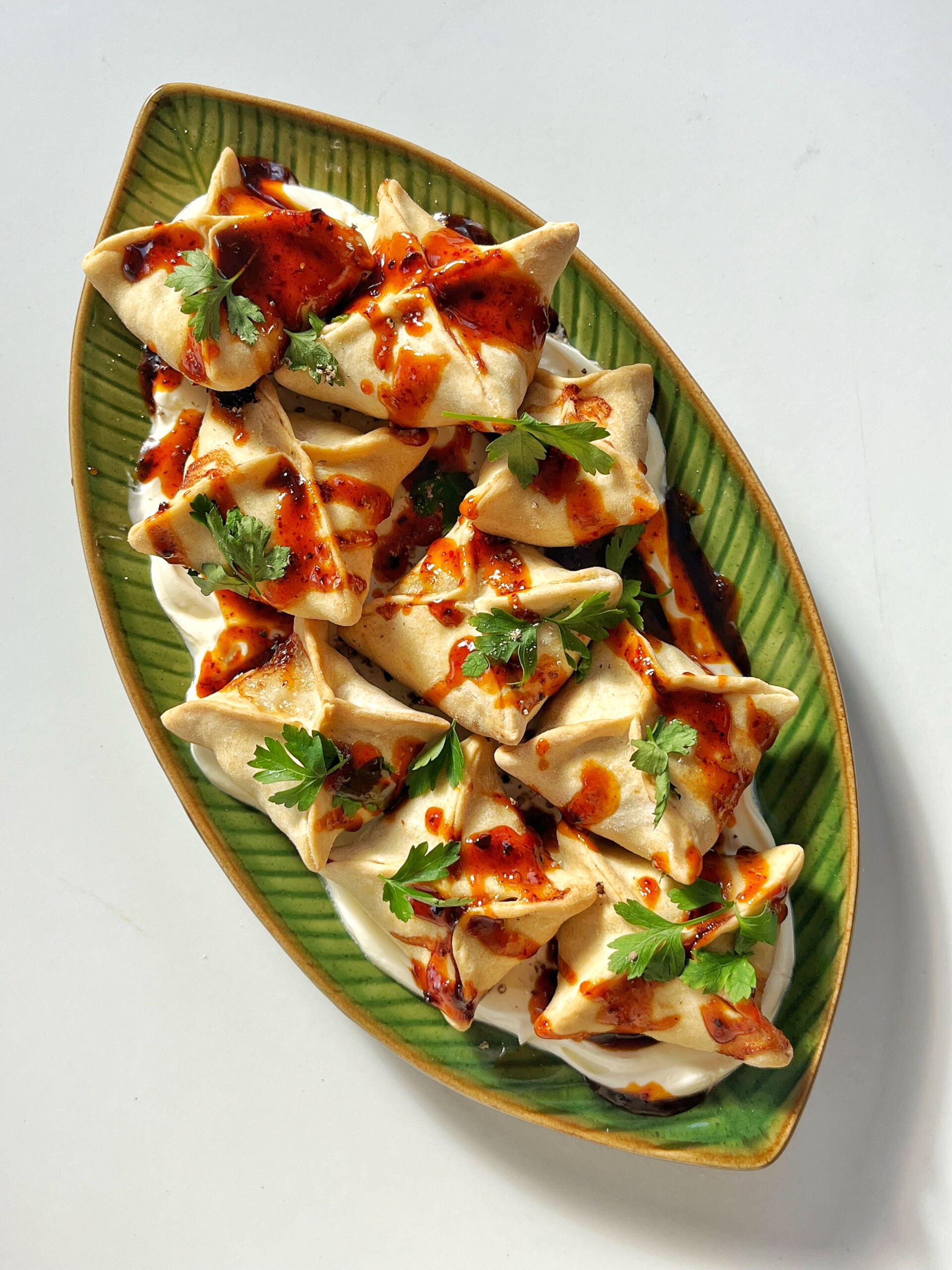 Shot of honey harissa sausage dumplings on green plate.