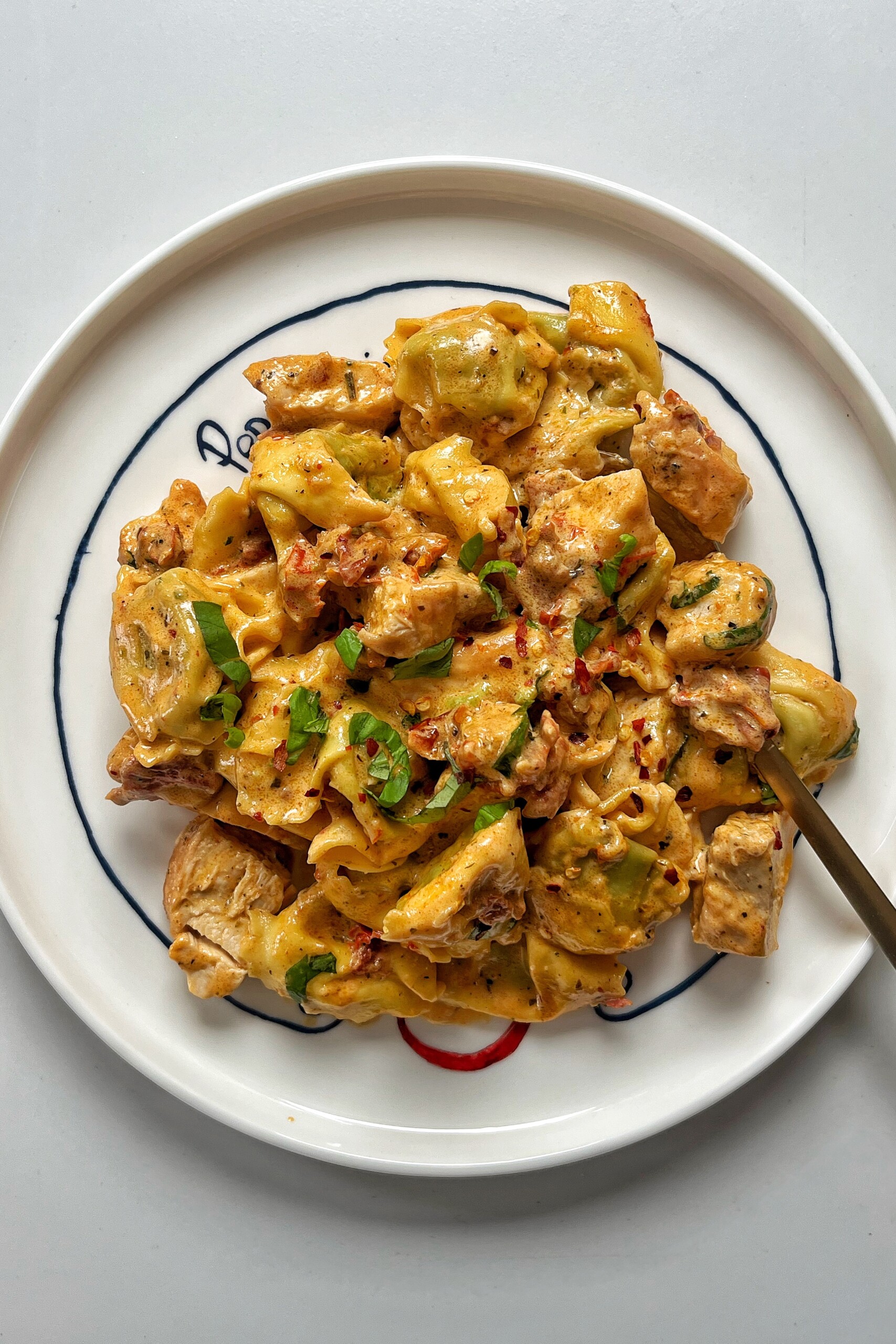 Marry me chicken tortellini on a white plate and white background.