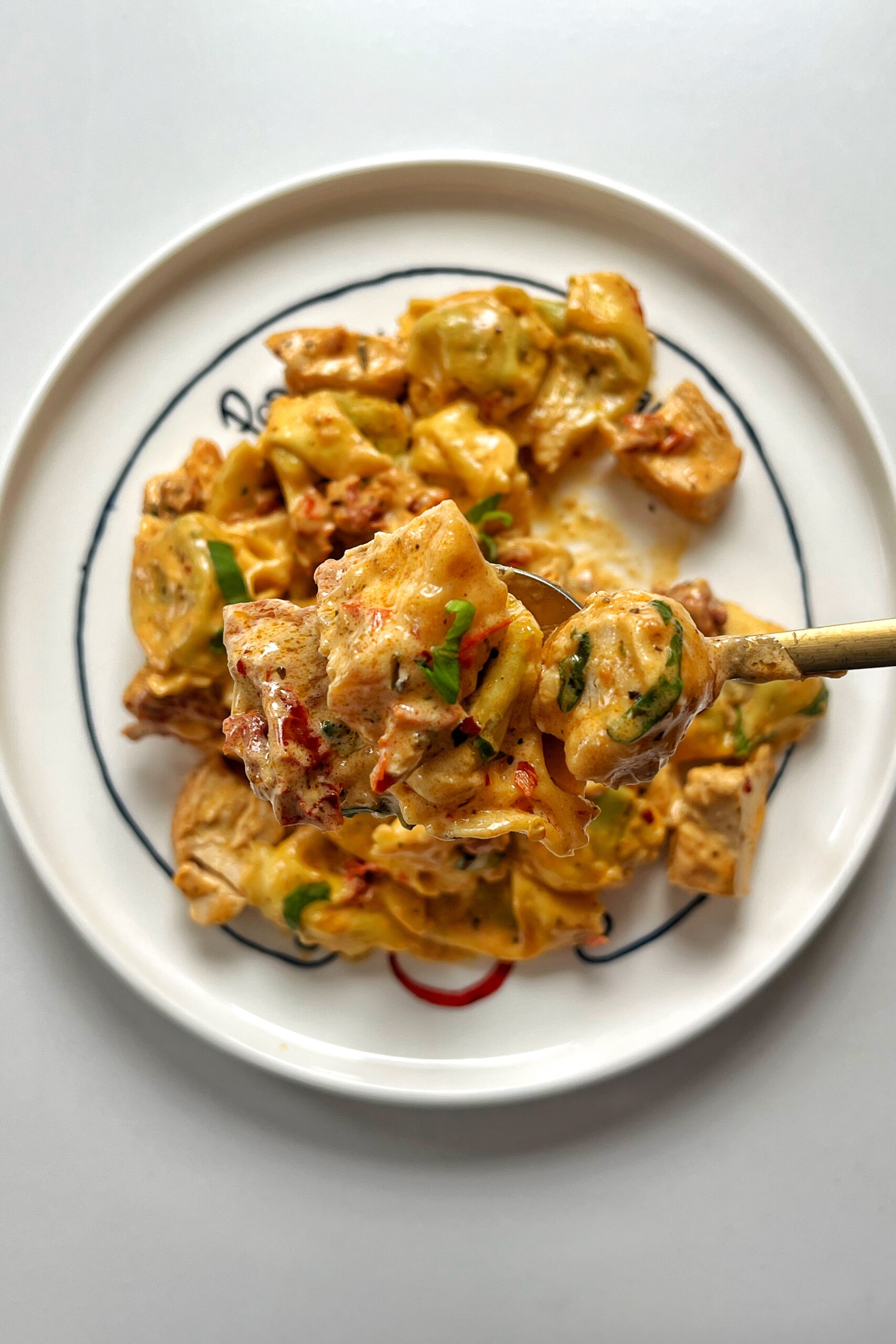 Holding up a fork of marry me chicken with tortellini.