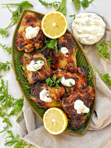 Air fryer greek yogurt chicken on a green plate with lemons.