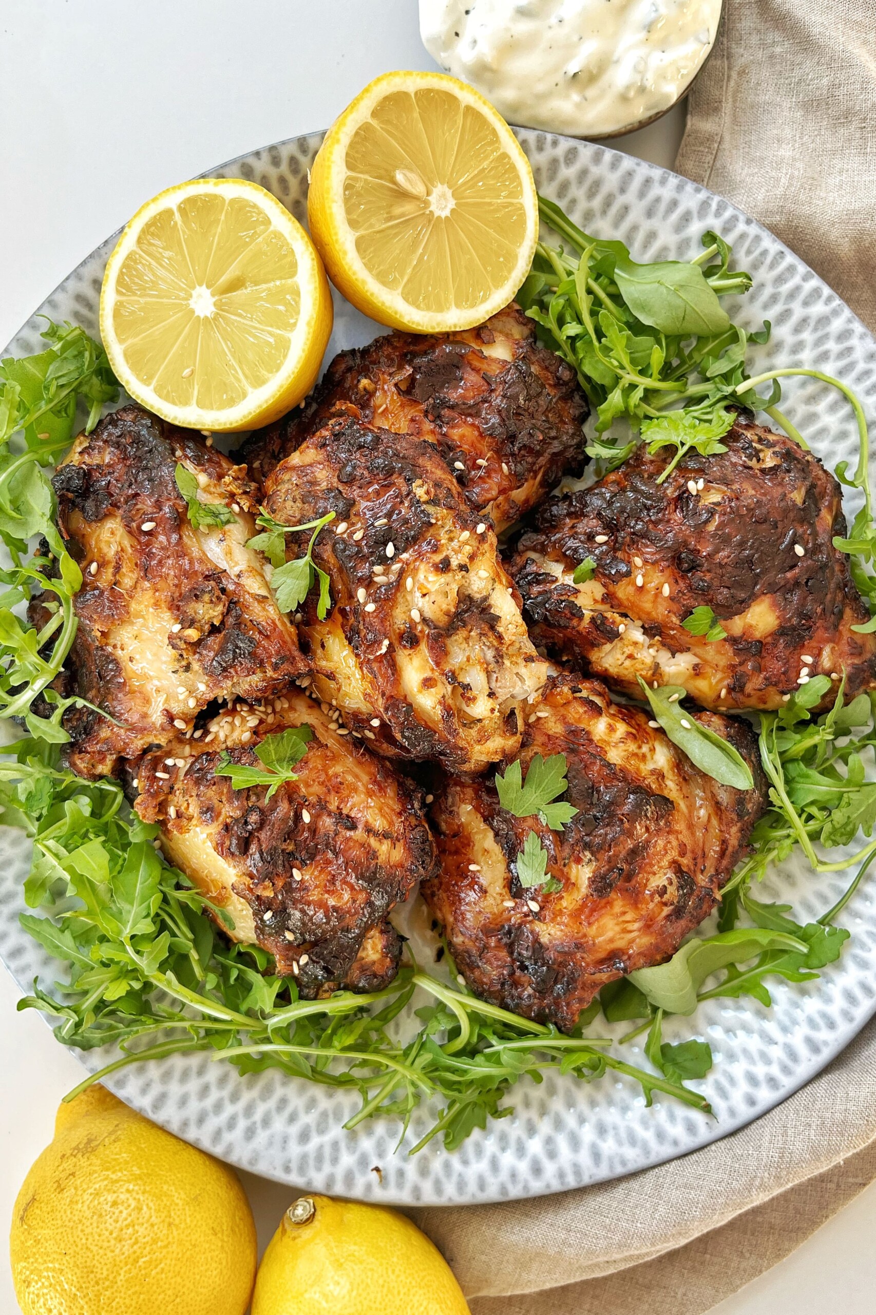 Plate of chicken thighs with lemon, rocket, and tzatziki.