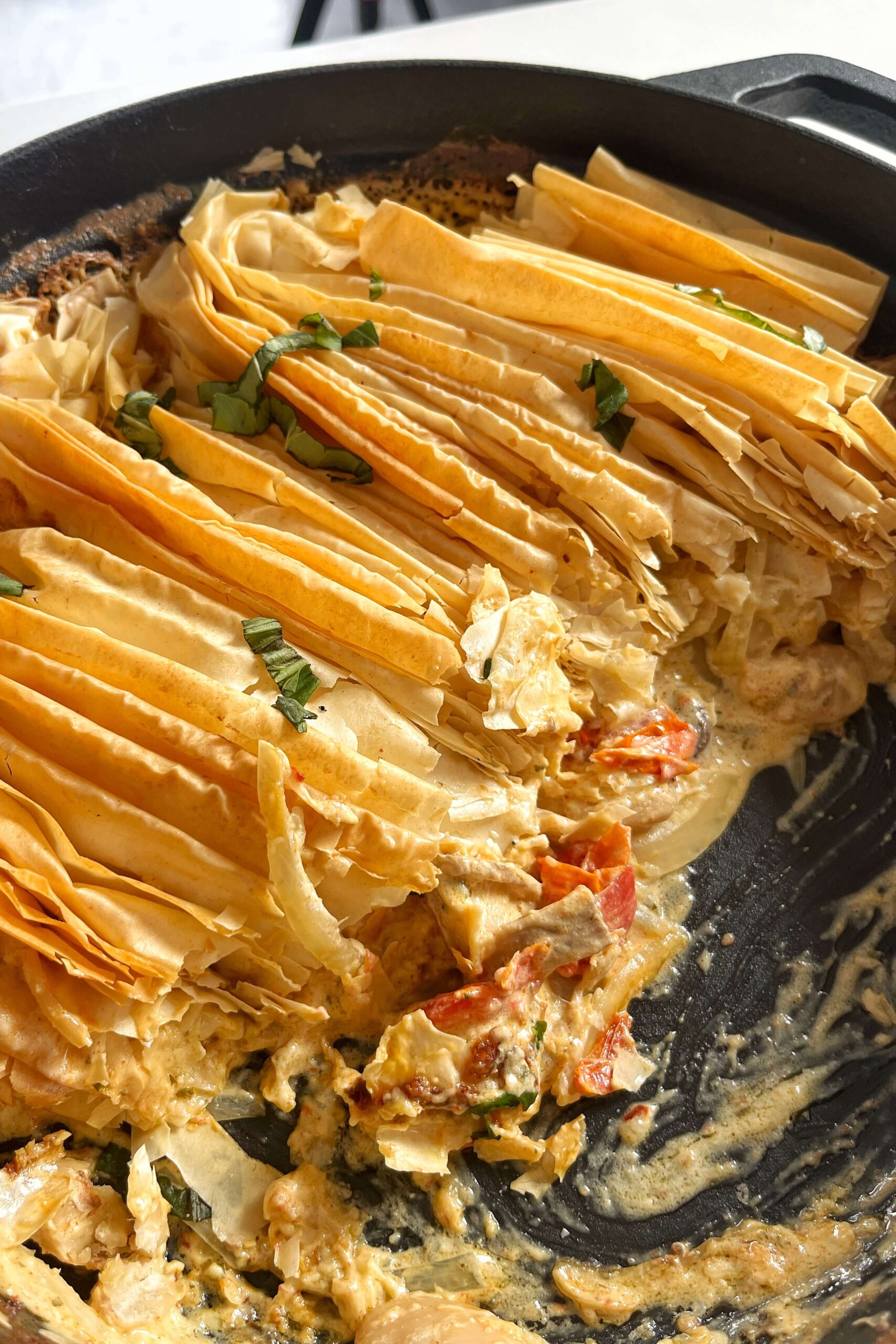 Crispy filo pastry with a Boursin filling underneath in black pan.