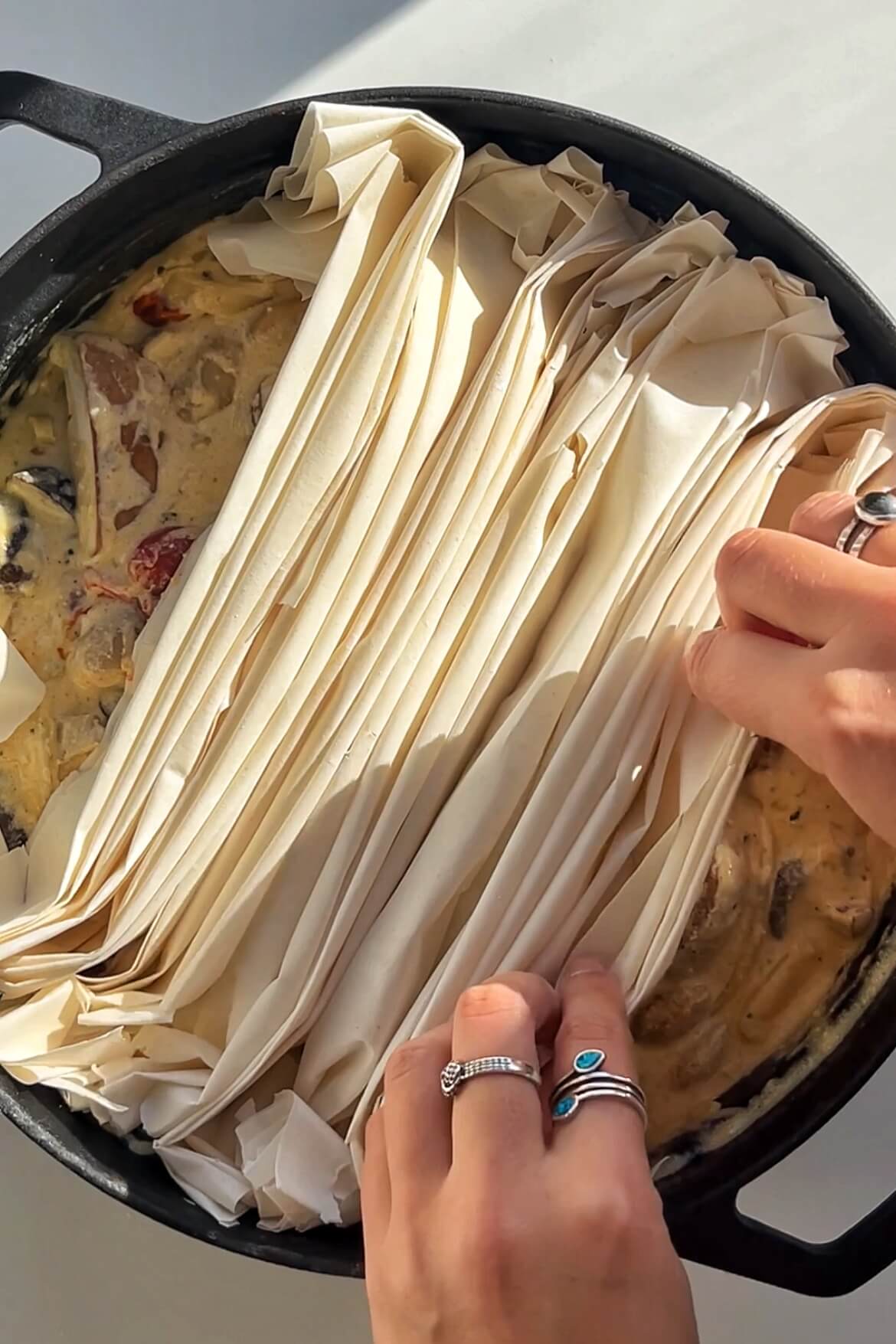 Placing filo pastry onto the surface of a pie filling.