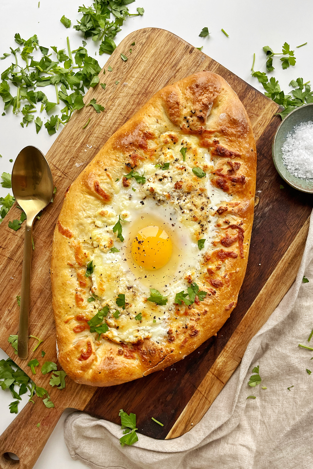Cheese boat pie with egg in the middle on a brown wooden board.