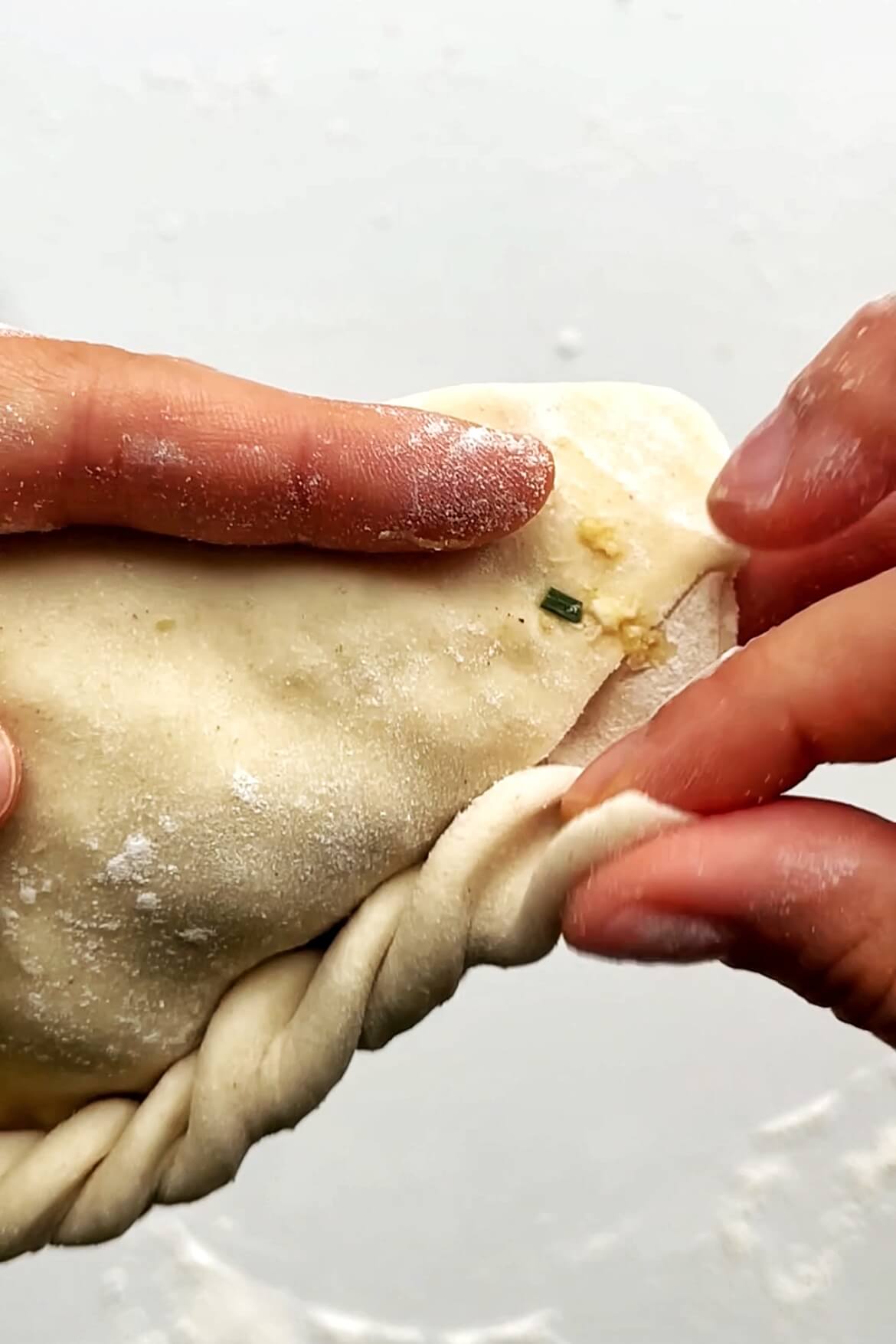 Pleating a chive pocket dumplings.
