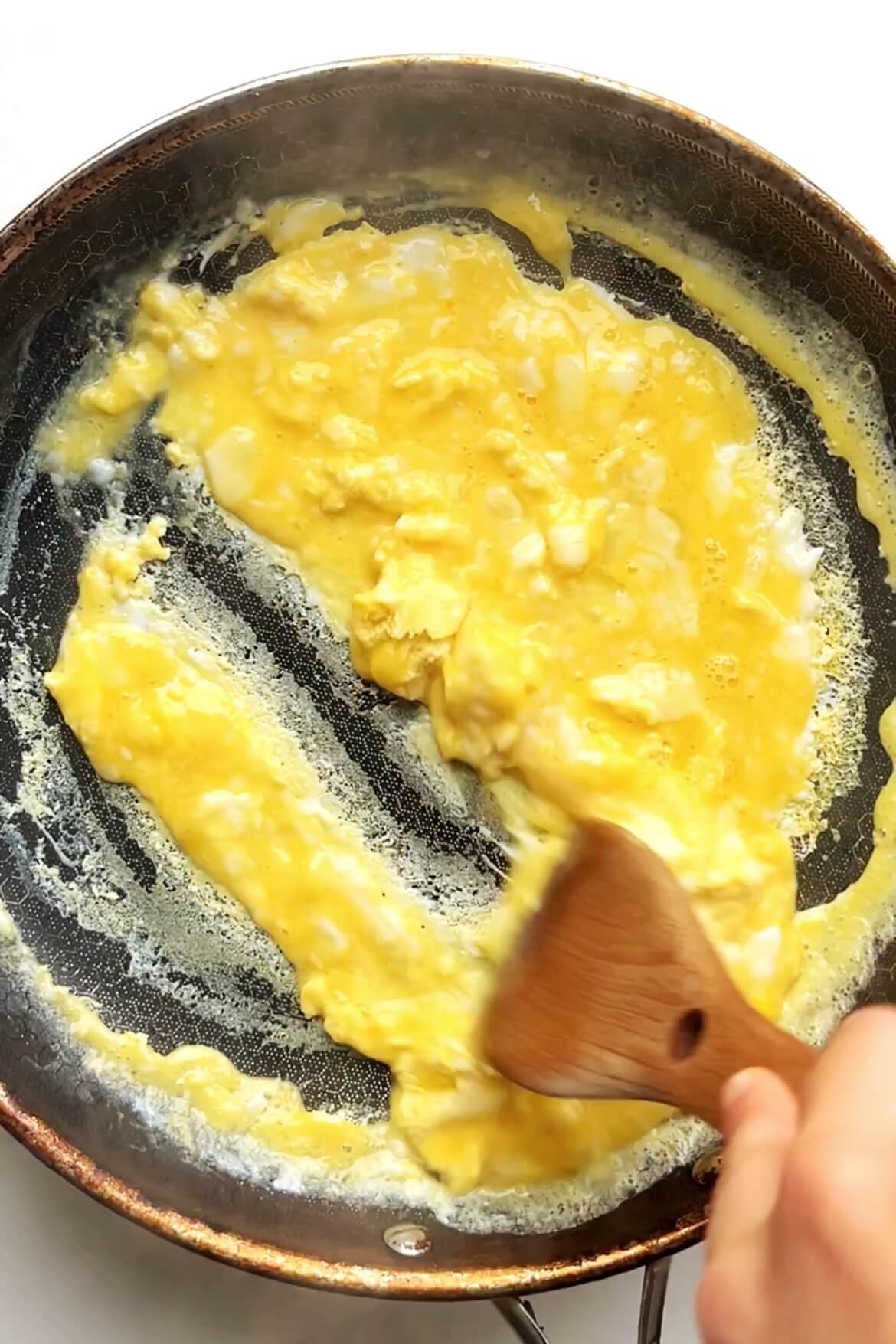 Making scrambled egg in black pan.