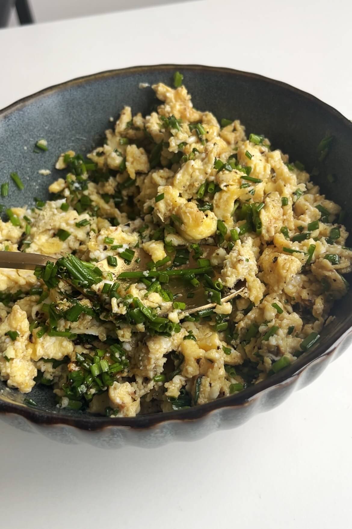 Mixture of cooked chives and eggs in bowl.