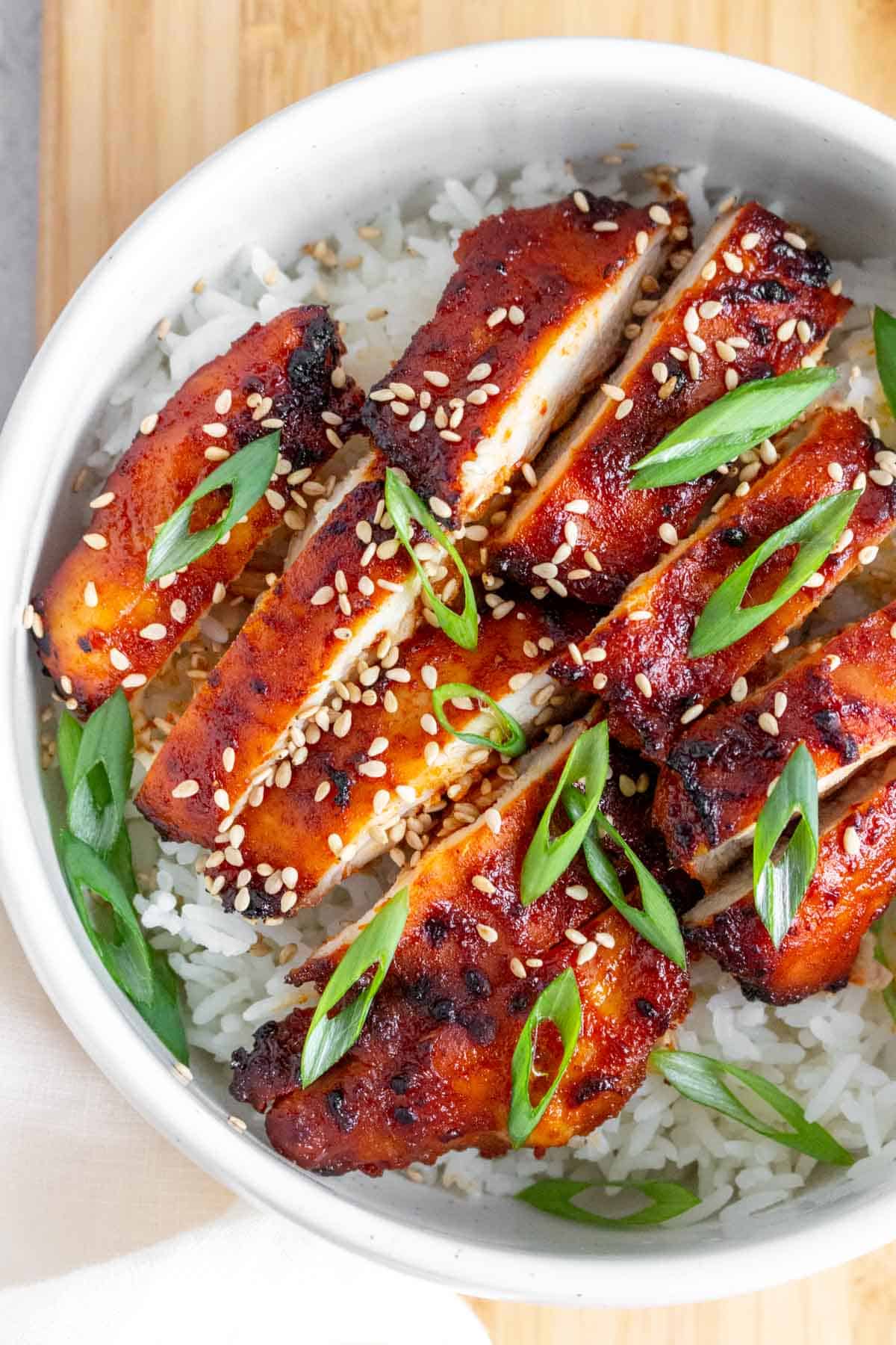 Air fryer gochujang chicken on rice in a white bowl.