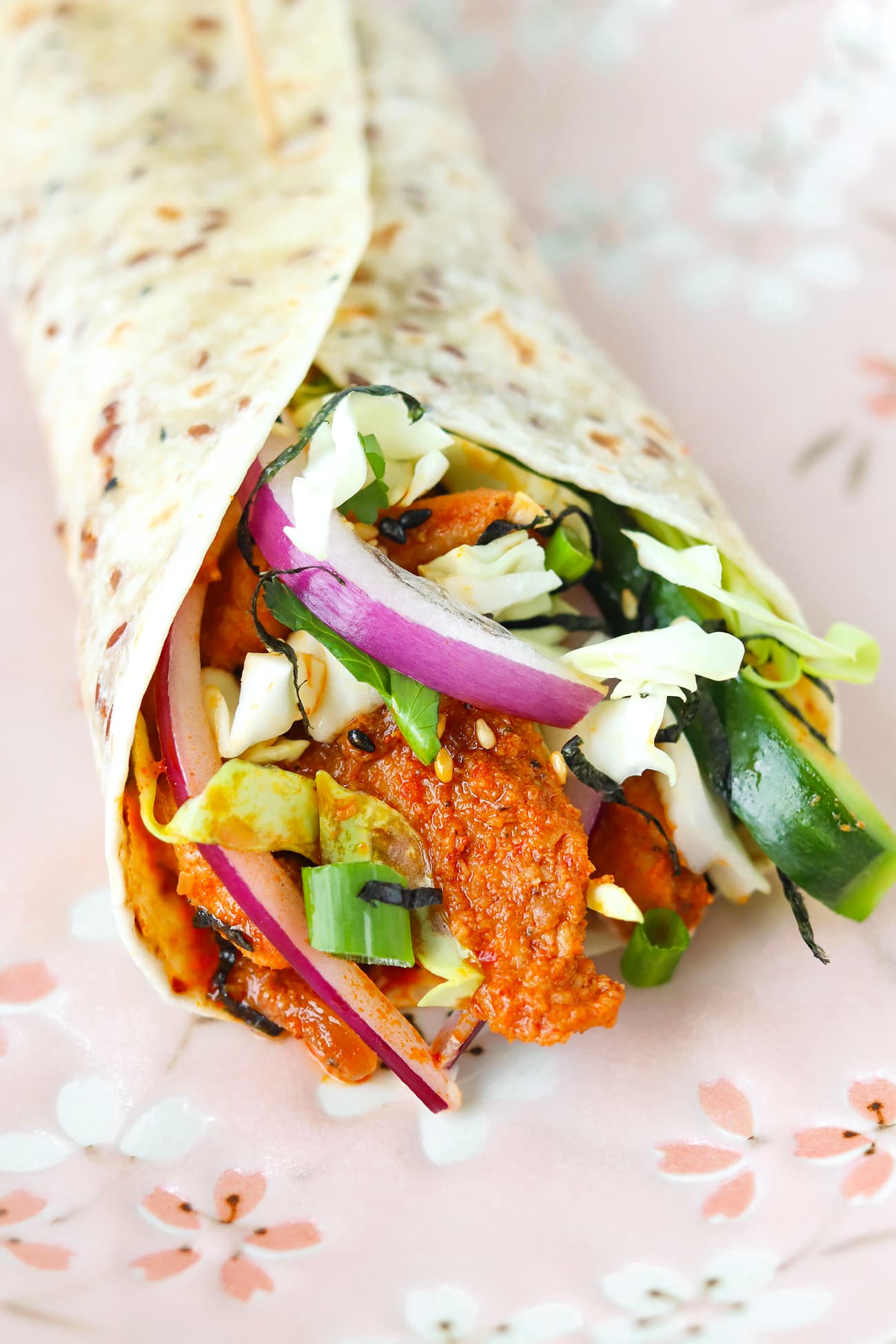 Gochujang chicken wrap with sauce and red onion.