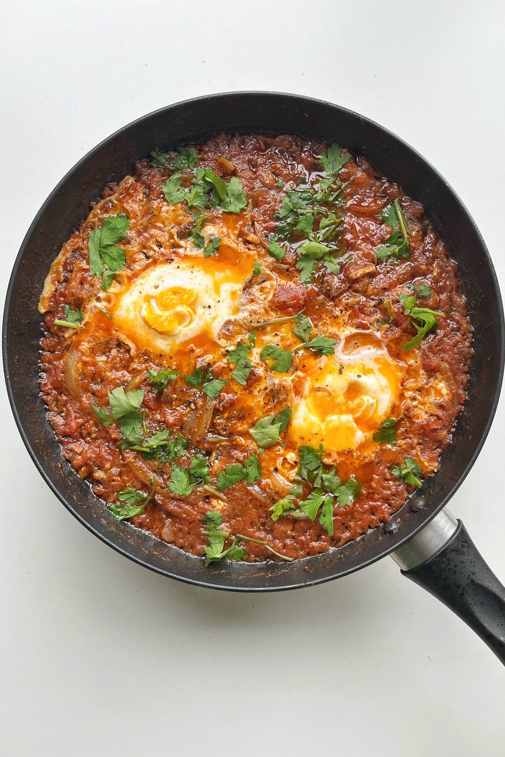Finished sardines and eggs in black pan.