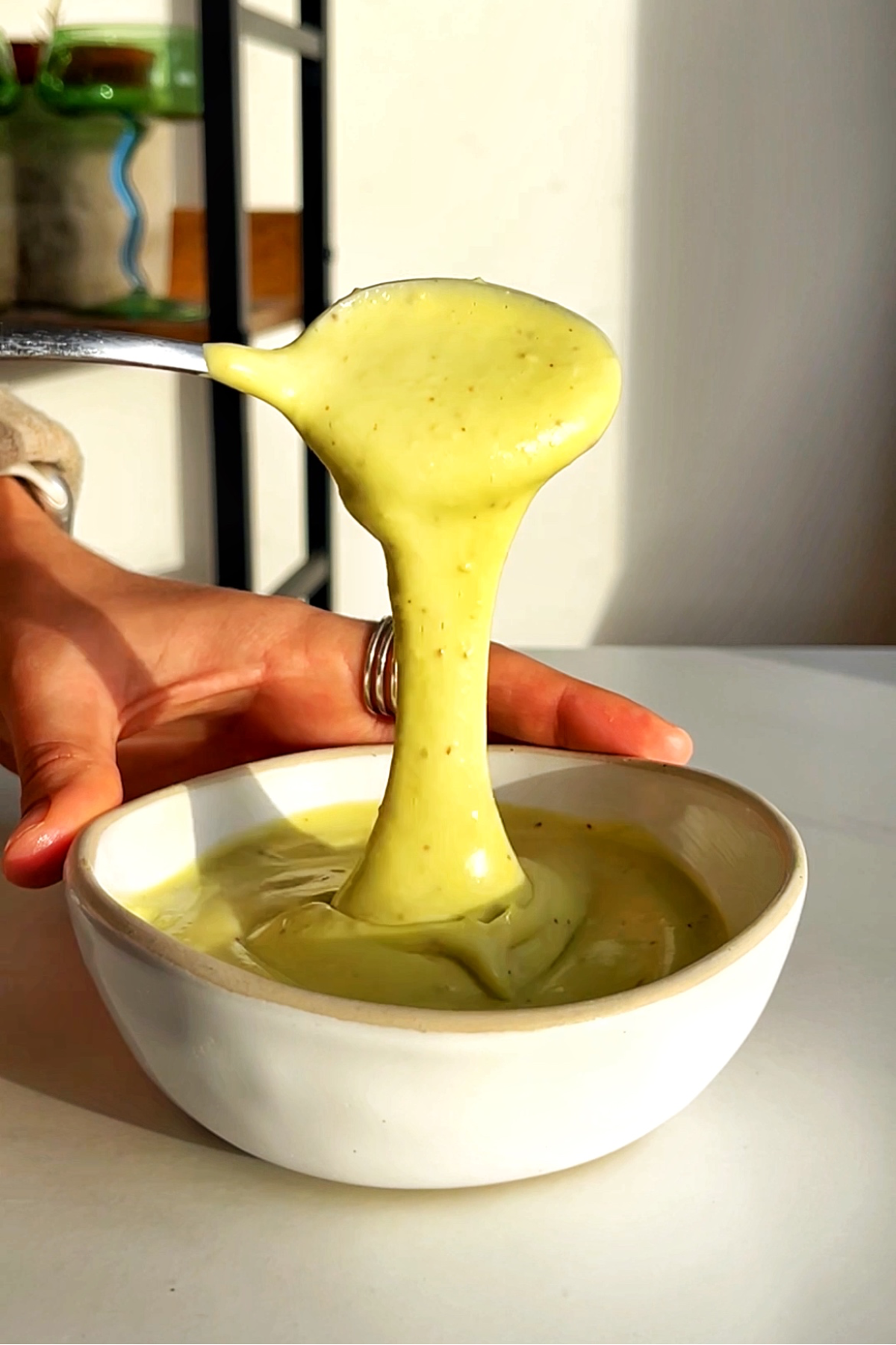 Green avocado drizzle in white bowl.
