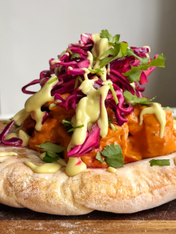 naan bread topped with butter curry, red cabbage, coriander, and avocado drizzle.