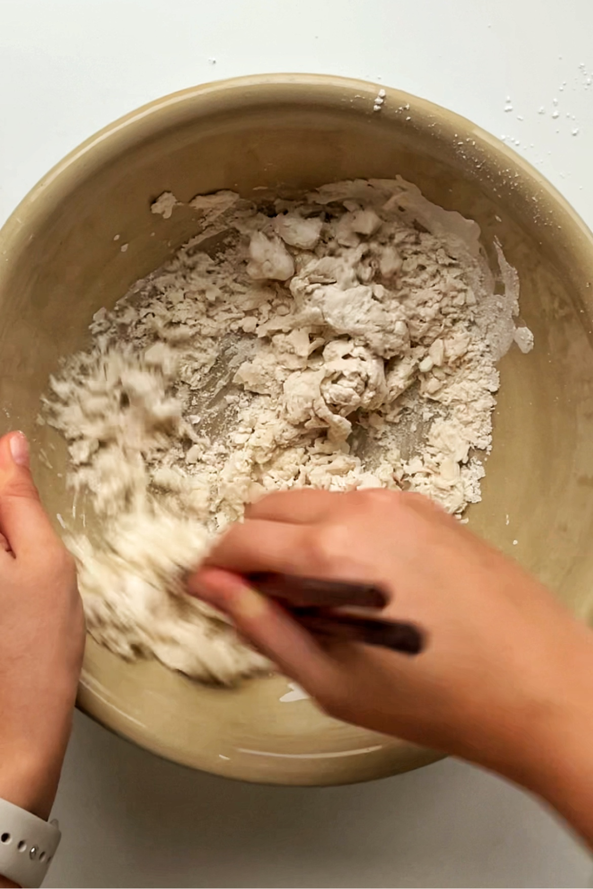Mixing flour with water in a large bowl with chopsticks.