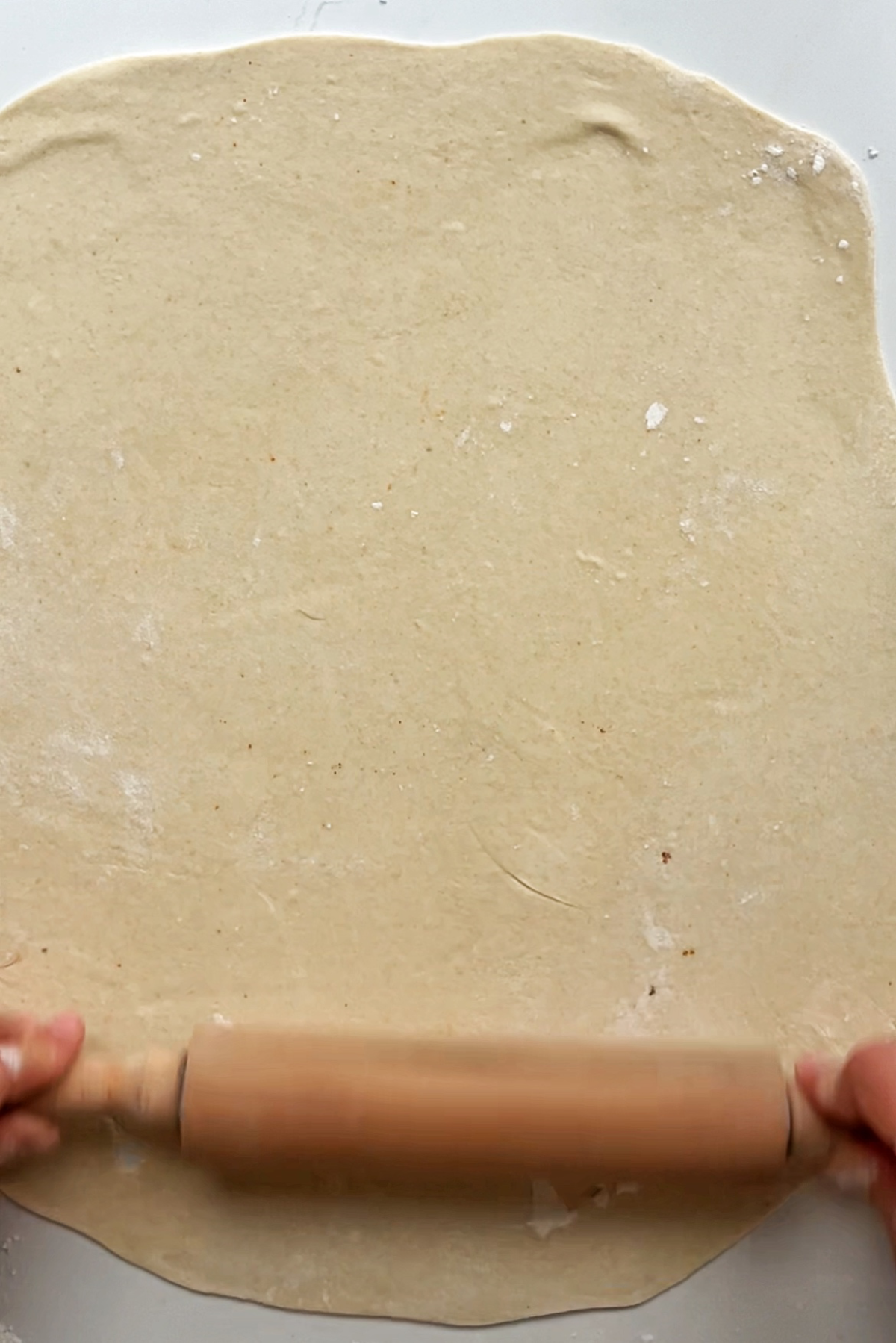 Rolling out a piece of dough into a large sheet.