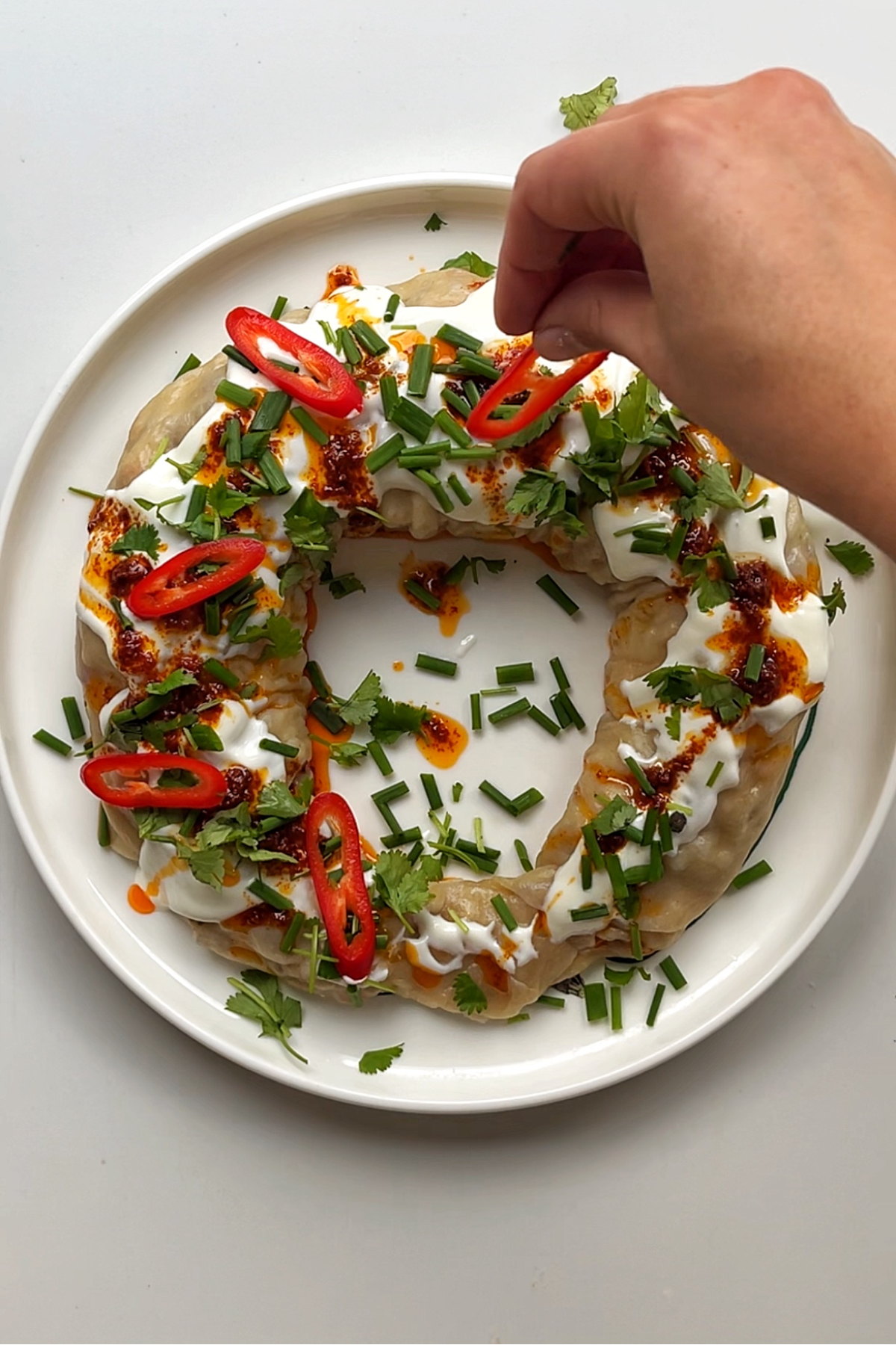 Garnishing the dumpling wreath with red chilli slices.