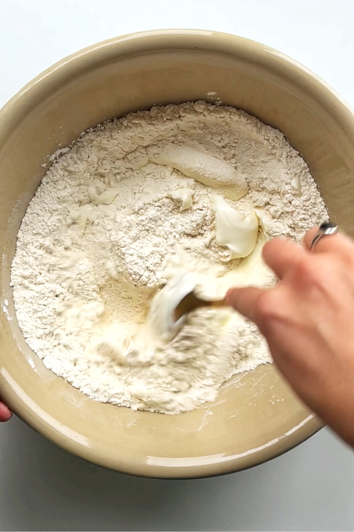 Mixing self-raising flour and greek yogurt in a bowl.