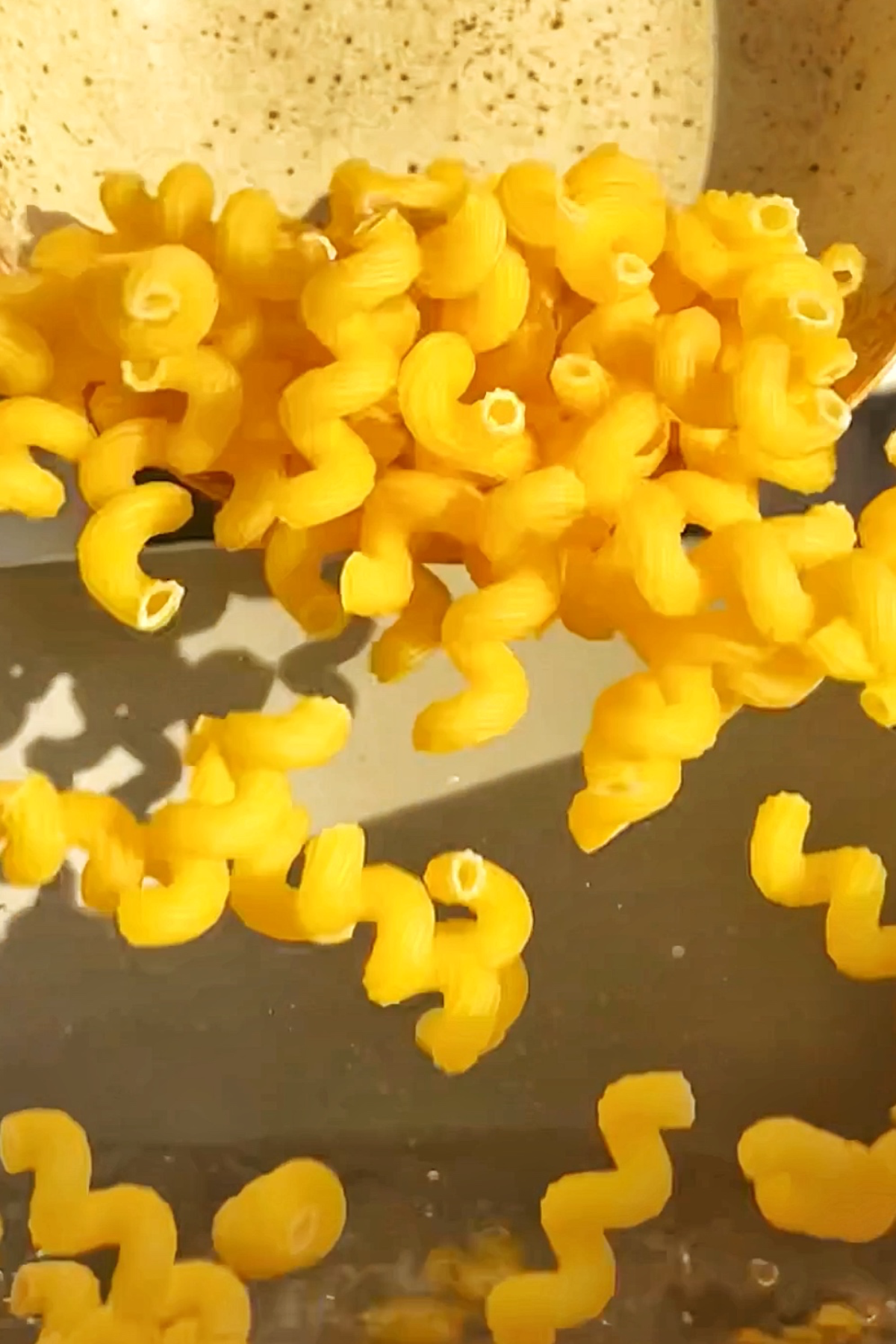 Pouring spirali pasta into a pan of water.