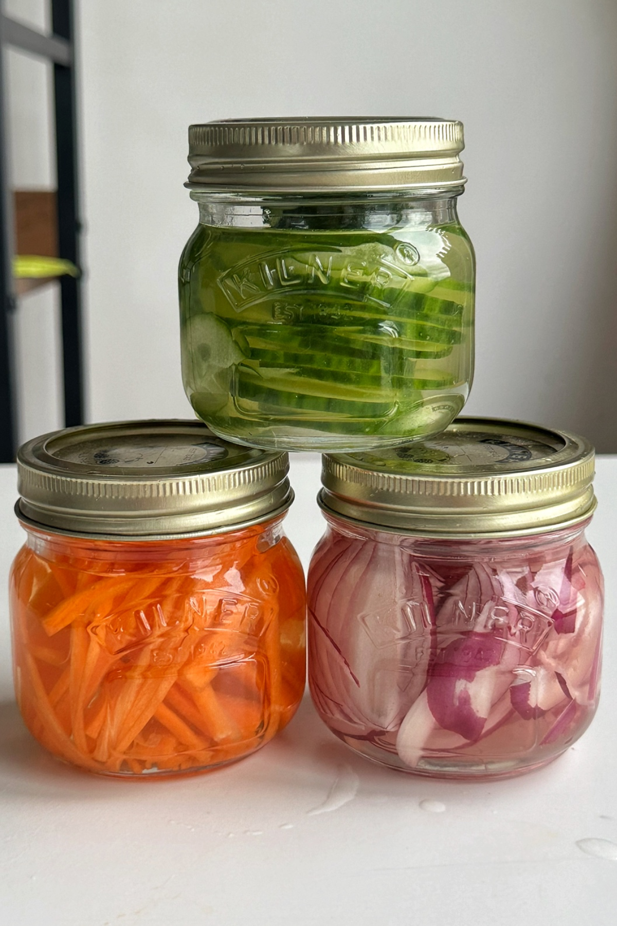 Three jarred pickles on top of each other.