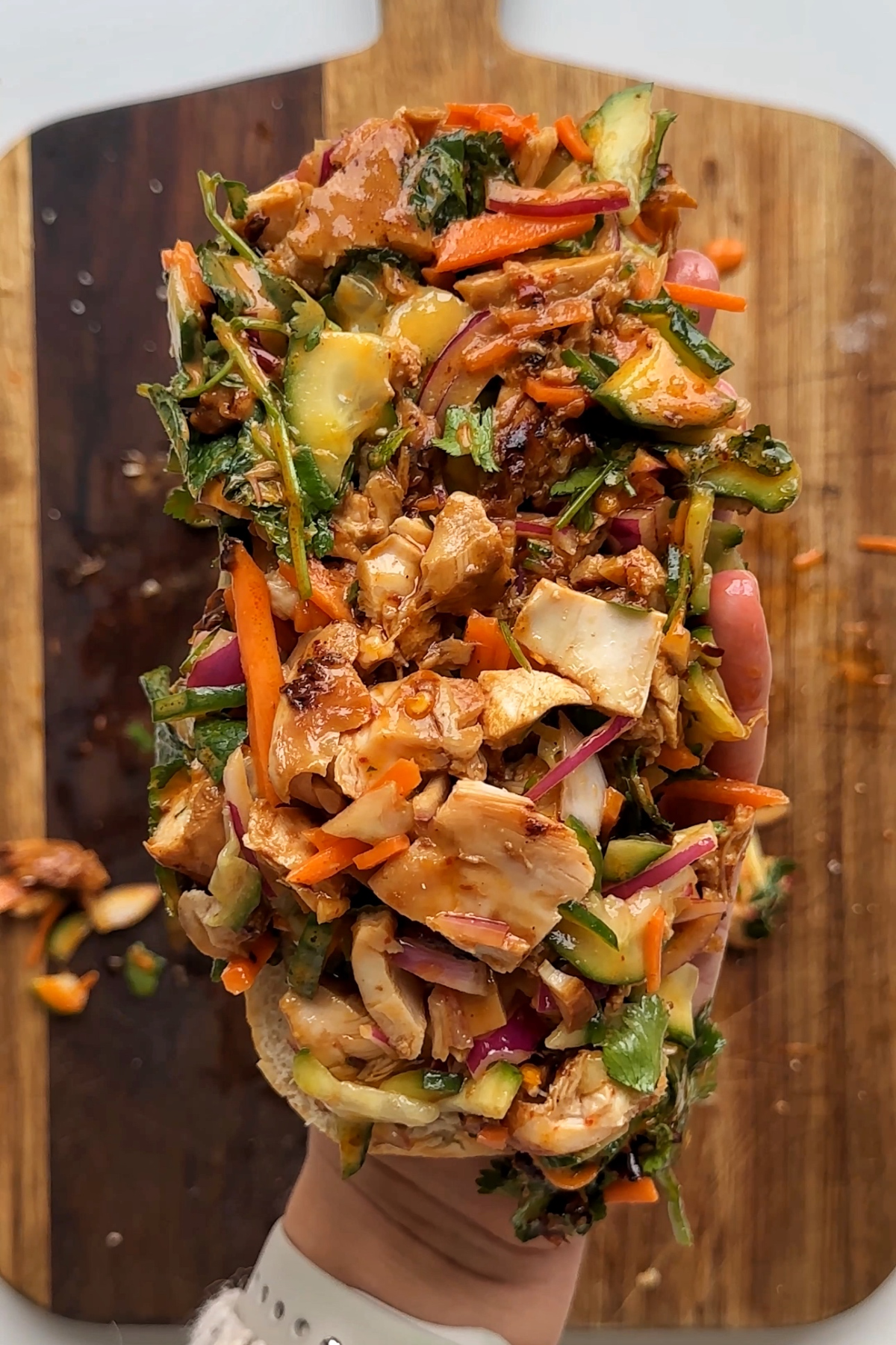 Holding up the half of the sandwich with the ingredients on top.