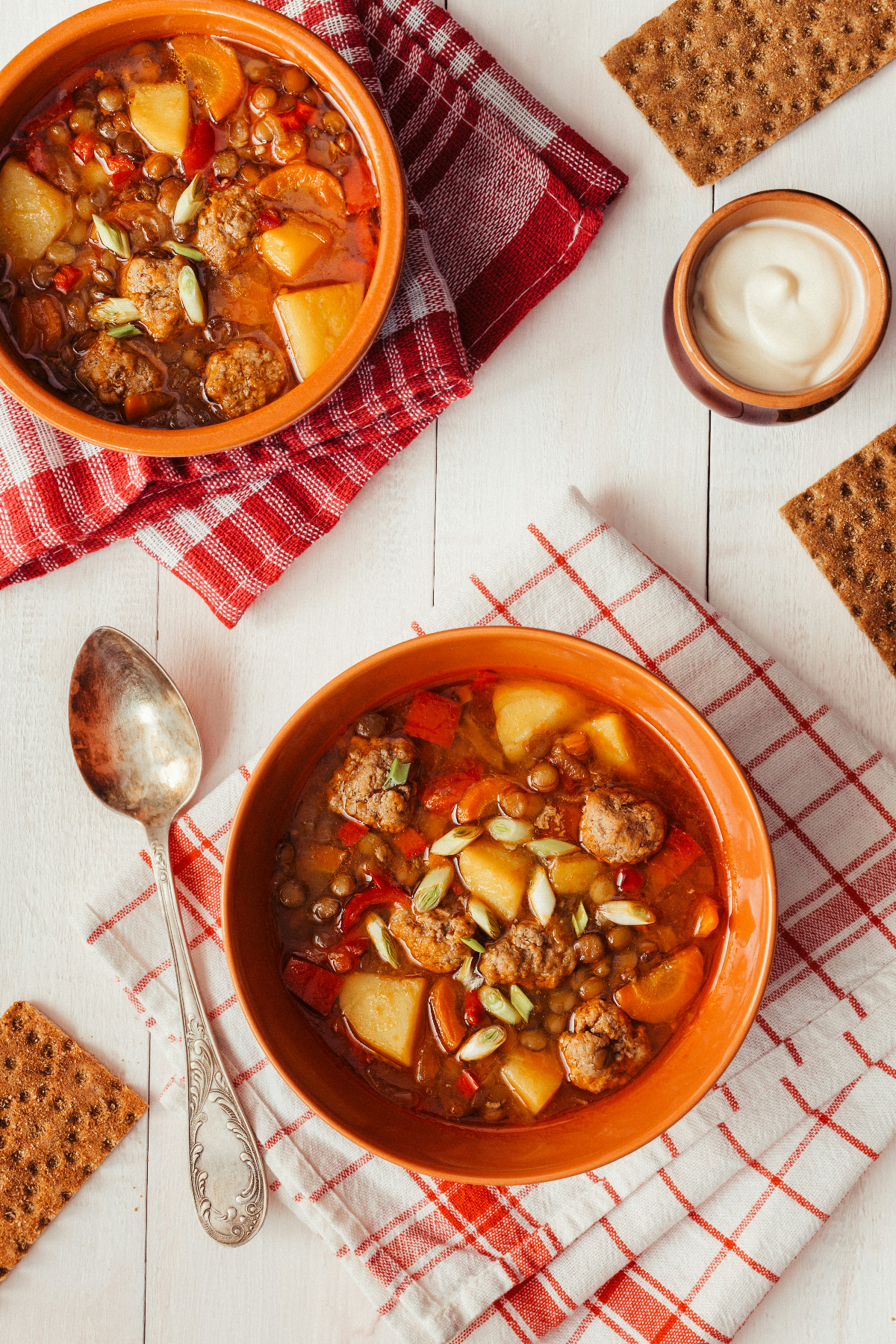 Bean stew in red bowls on a white table.