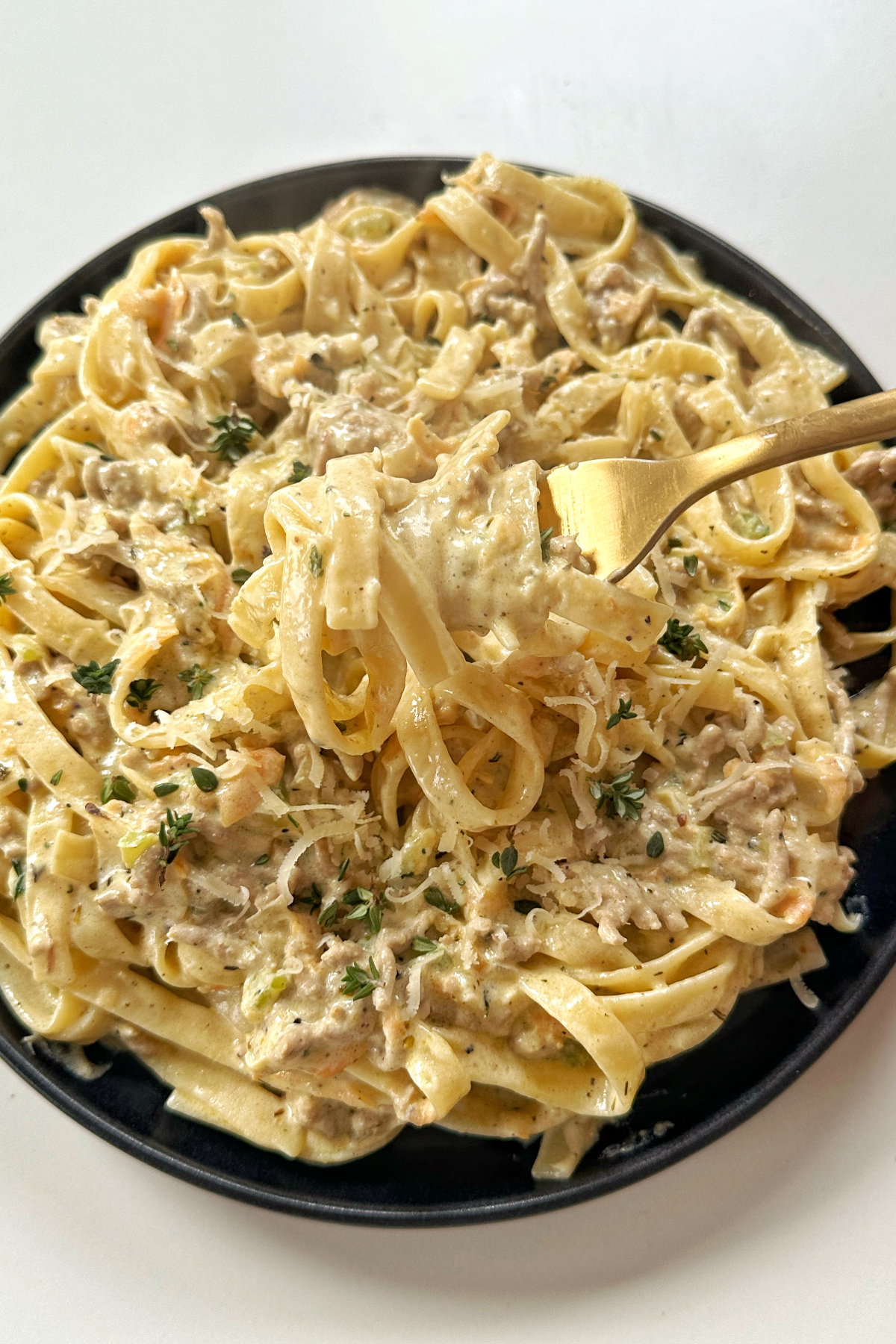 Lifting up pasta with a fork towards the camera.