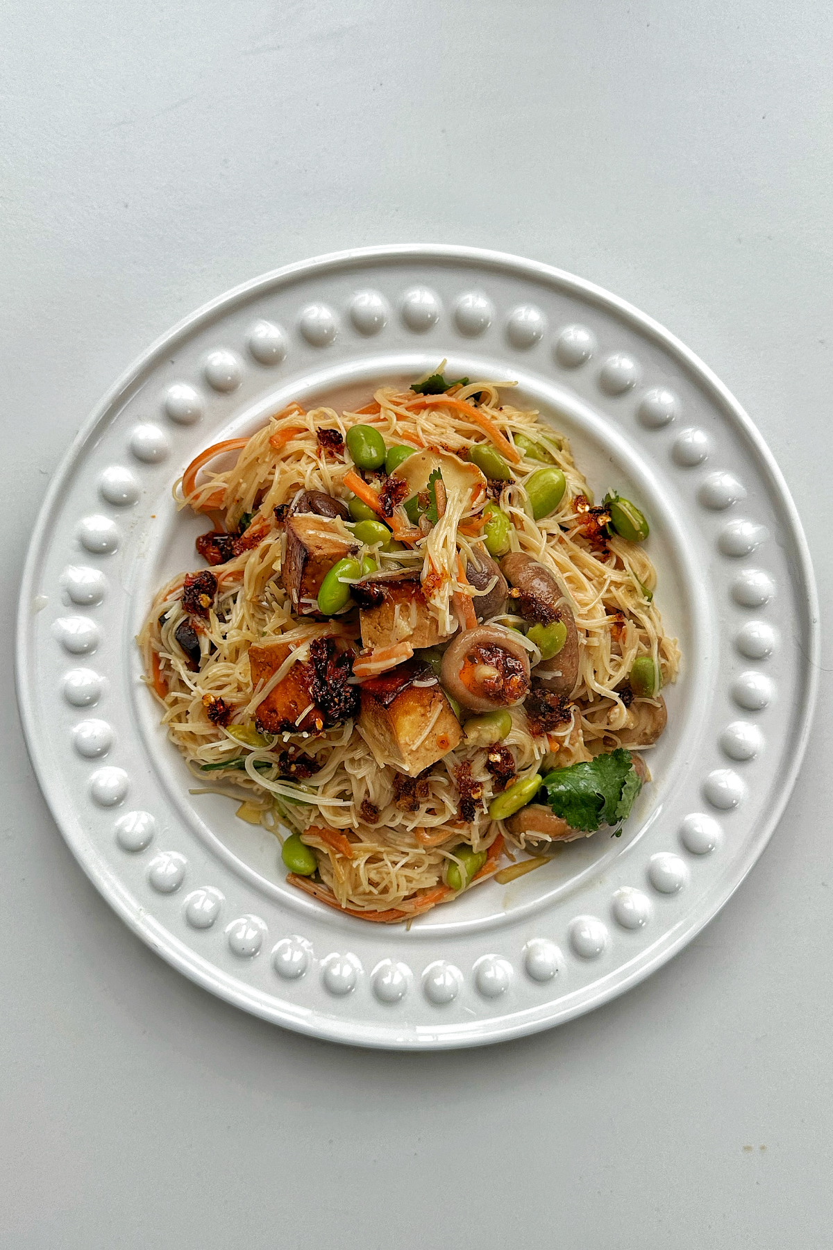 White plate with vermicelli noodles, vegetables, and tofu.