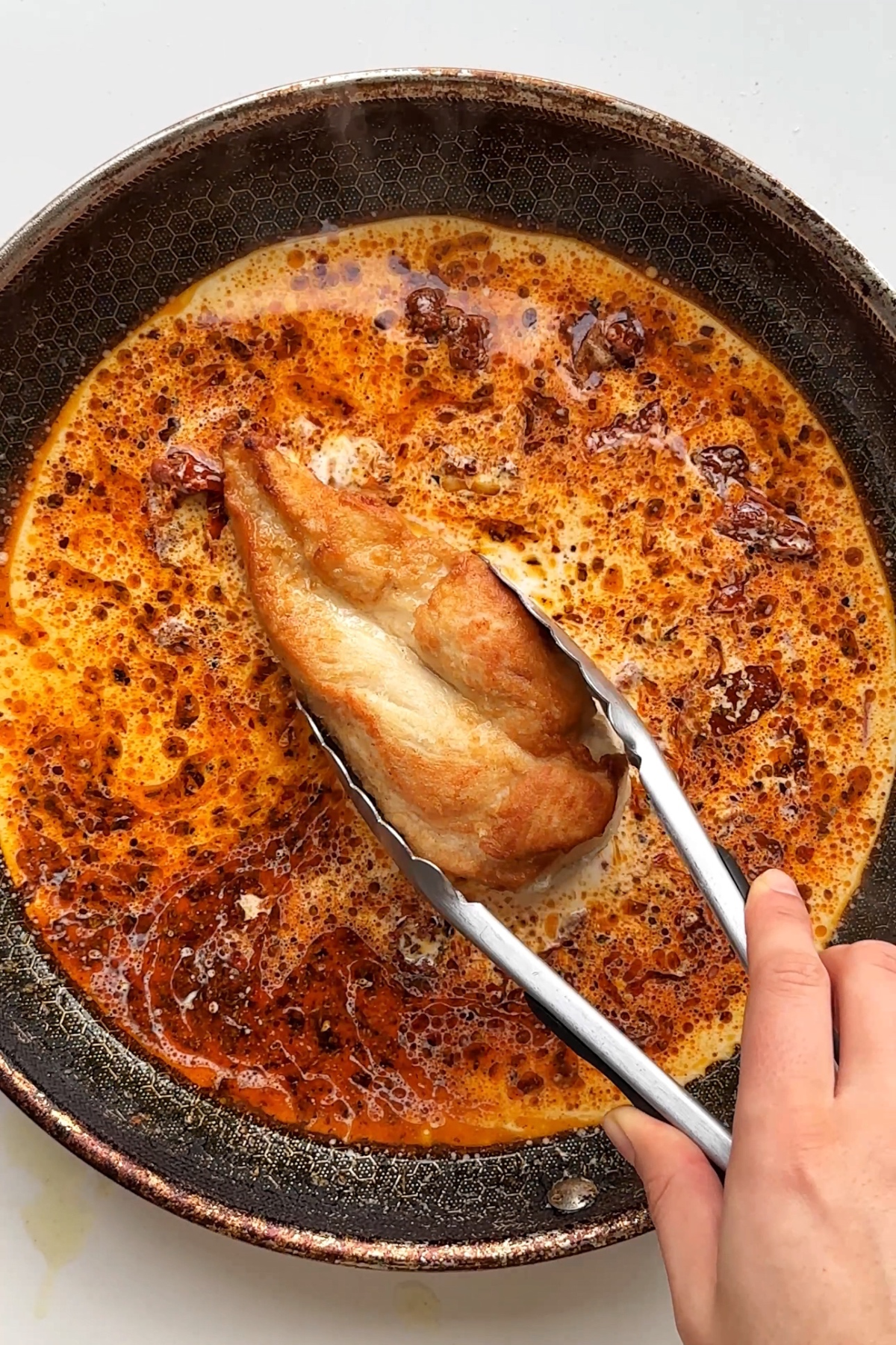Placing a chicken breast back into the marry me chicken creamy sauce. 