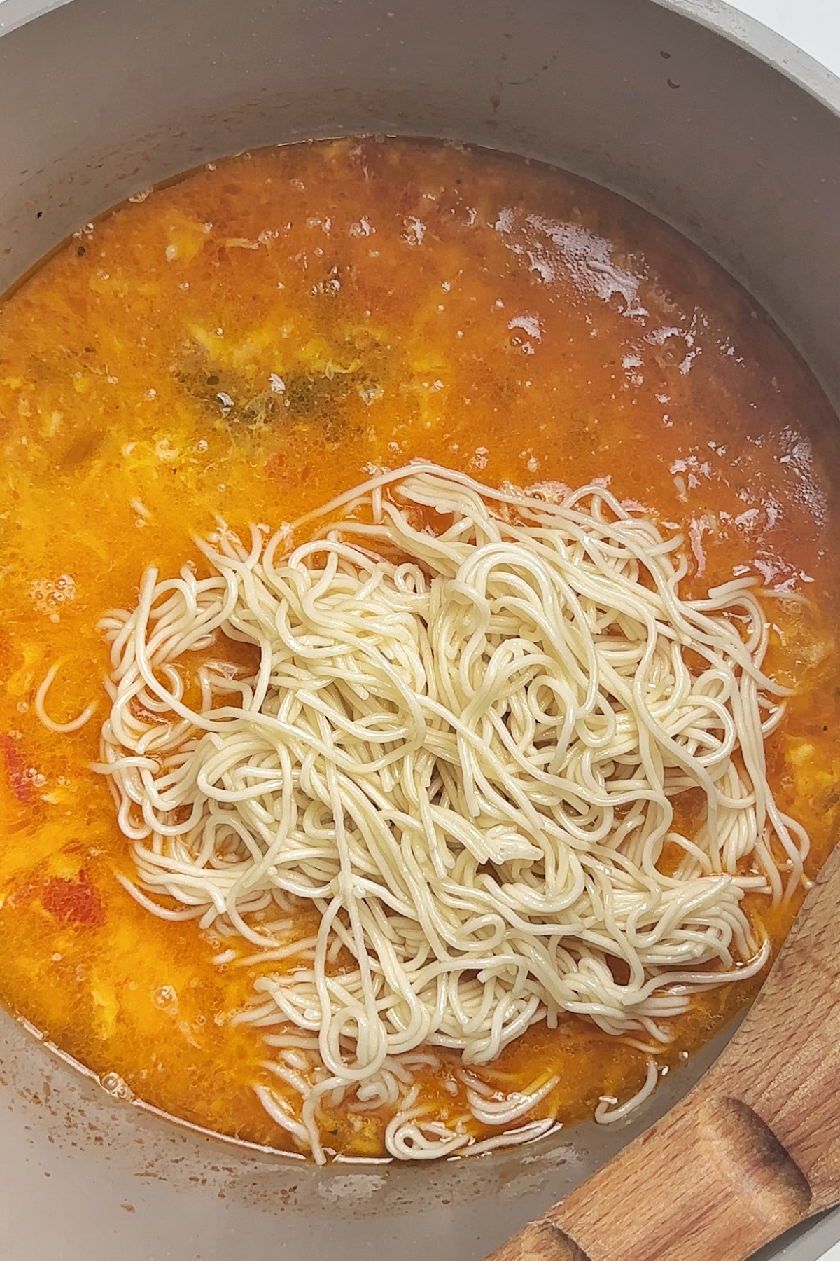 Noodles added to a tomato egg drop noodle soup.