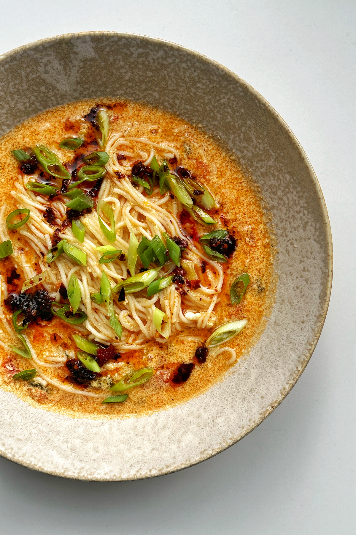 Side photo of a bowl of egg drop tomato noodle soup.