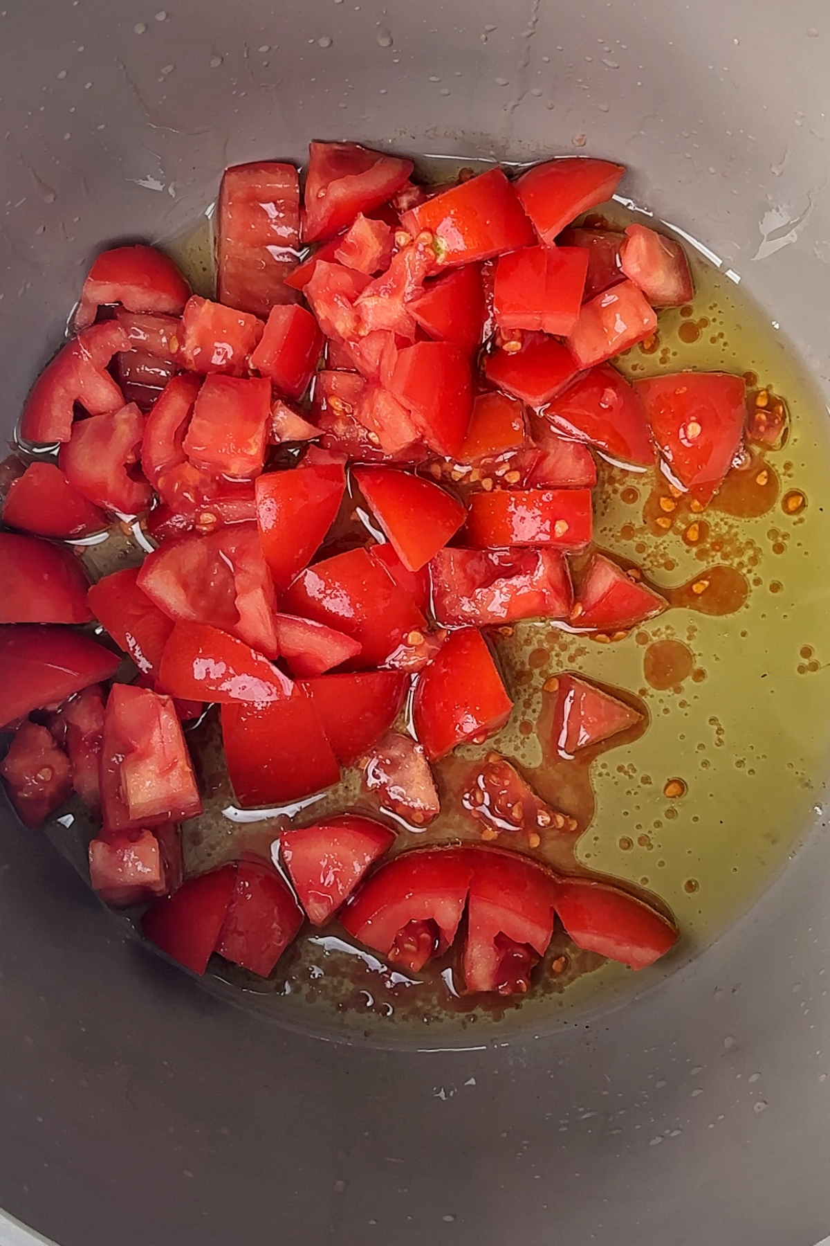 Frying tomatoes in a saucepan with oil.