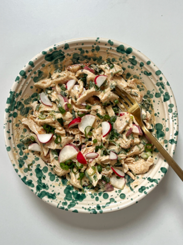Bowl with chicken salad inside and a fork coming out of it.