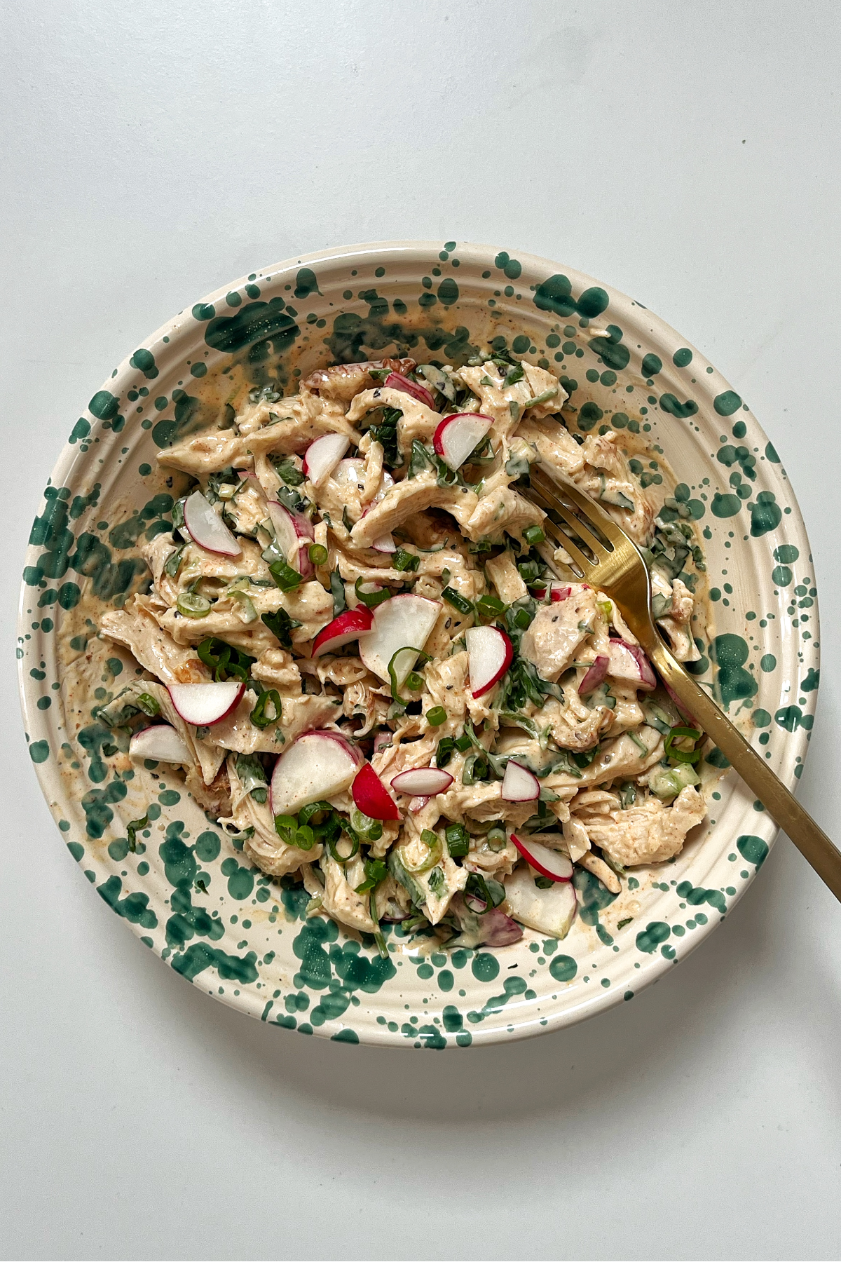 Bowl with chicken salad inside and a fork coming out of it.