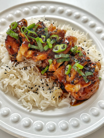 Close up of honey ginger chicken in a white bowl over rice.