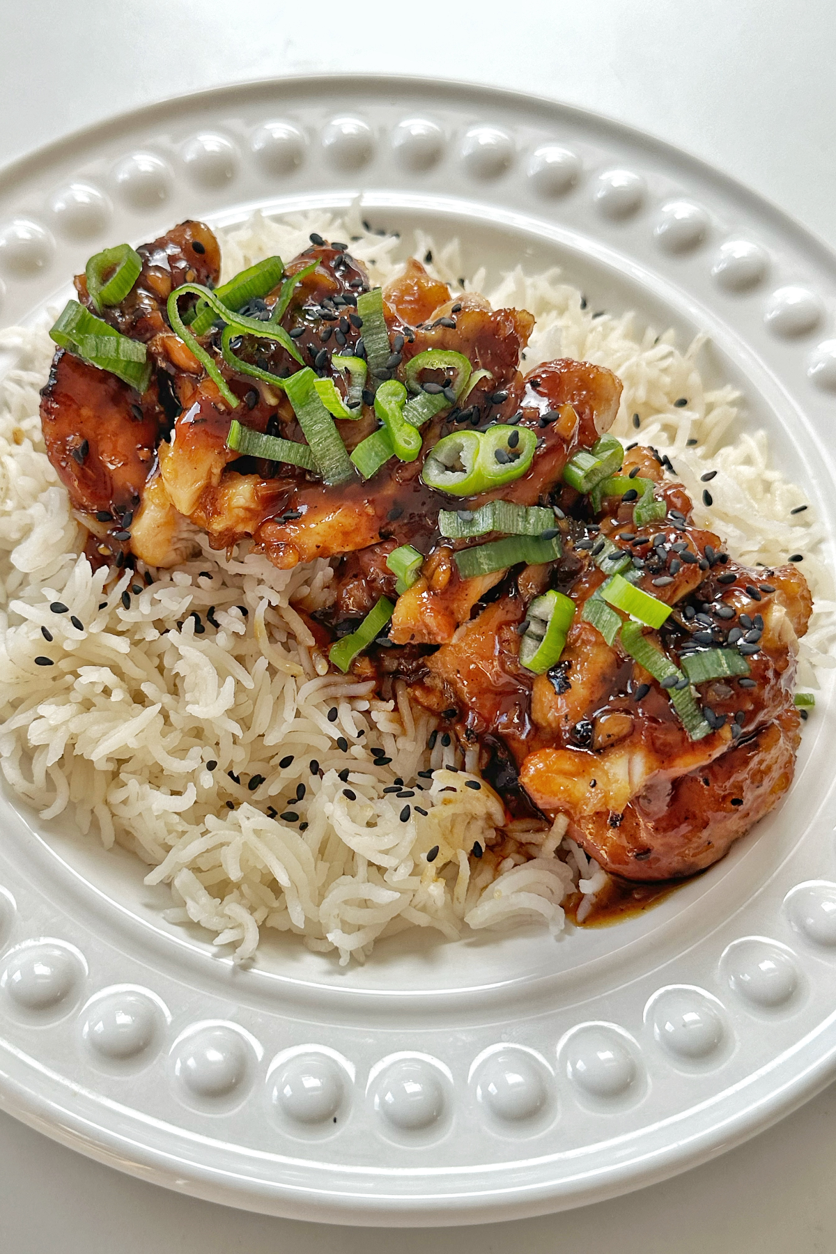 Close up of honey ginger chicken in a white bowl over rice.