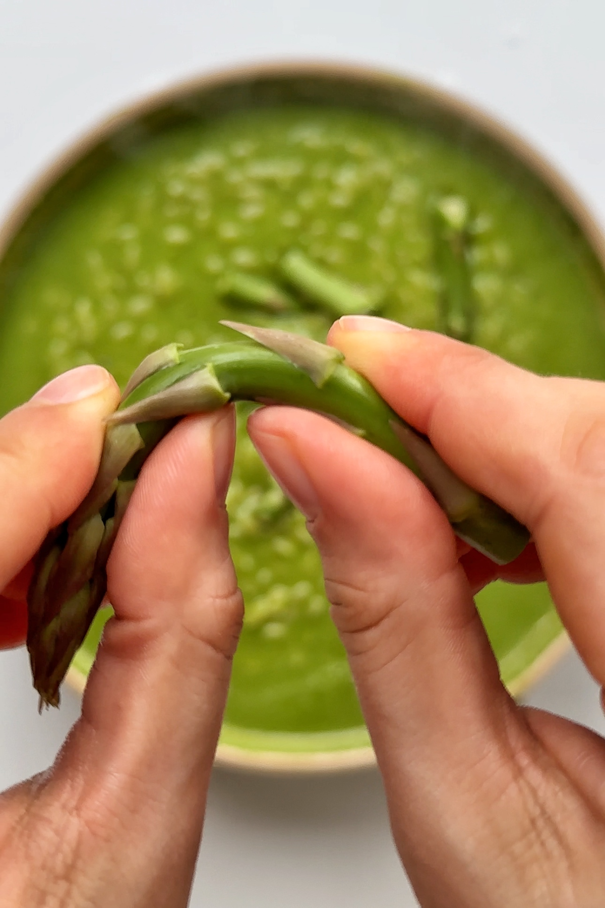 Breaking asparagus into the orzo frying pan with green sauce.