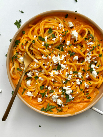 Pasta sauce sweet potato in a pan with feta cheese and parsley.