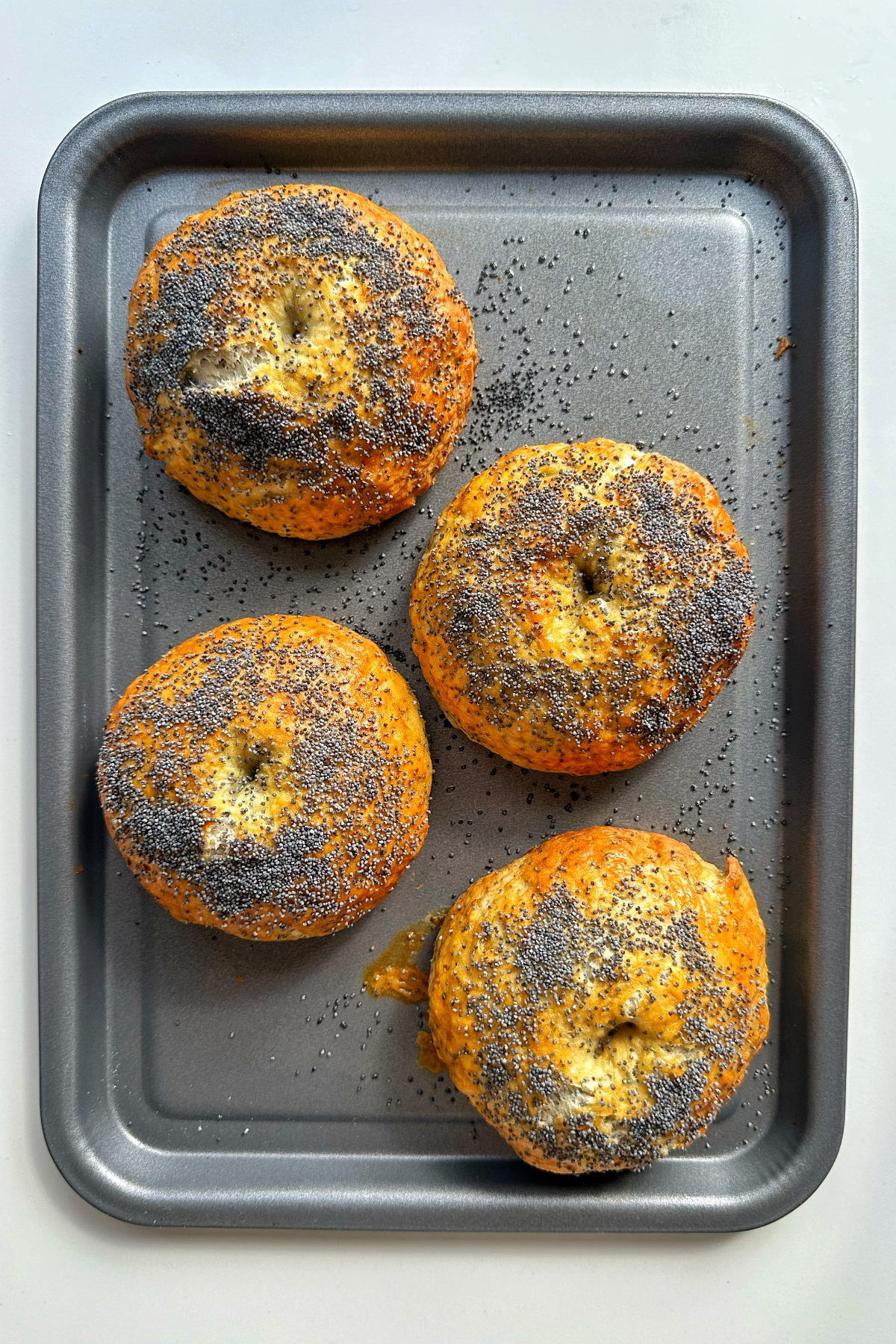 Baked bagels on a metal baking tray.